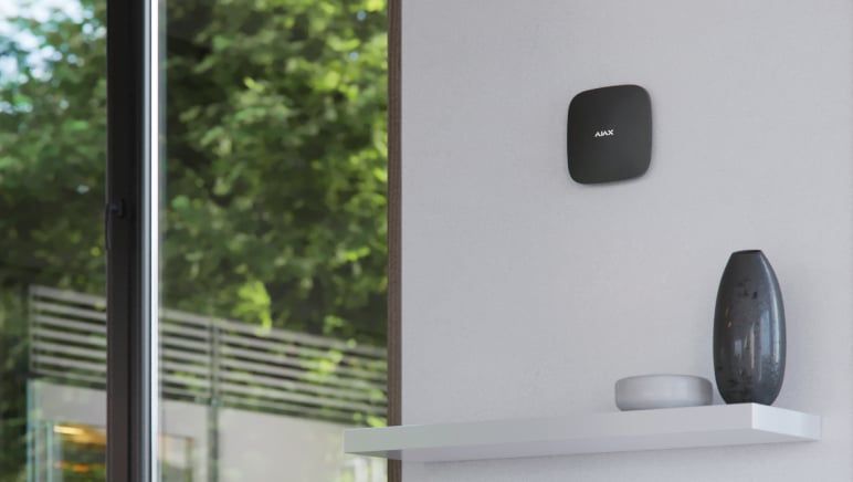 Ajax hub mounted on a wall above a shelf in a modern home