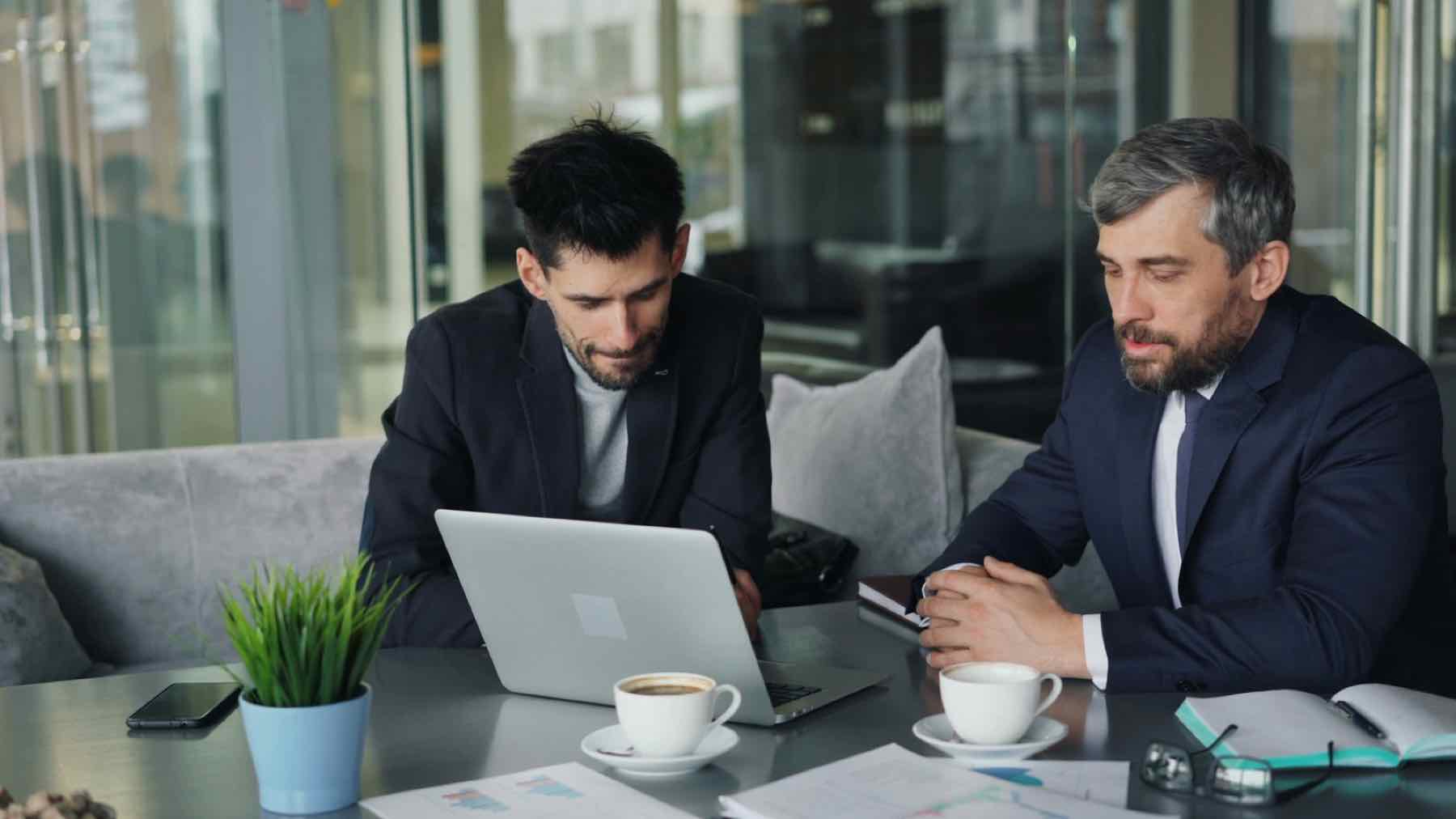 Manager coaching employee one-on-one at laptop